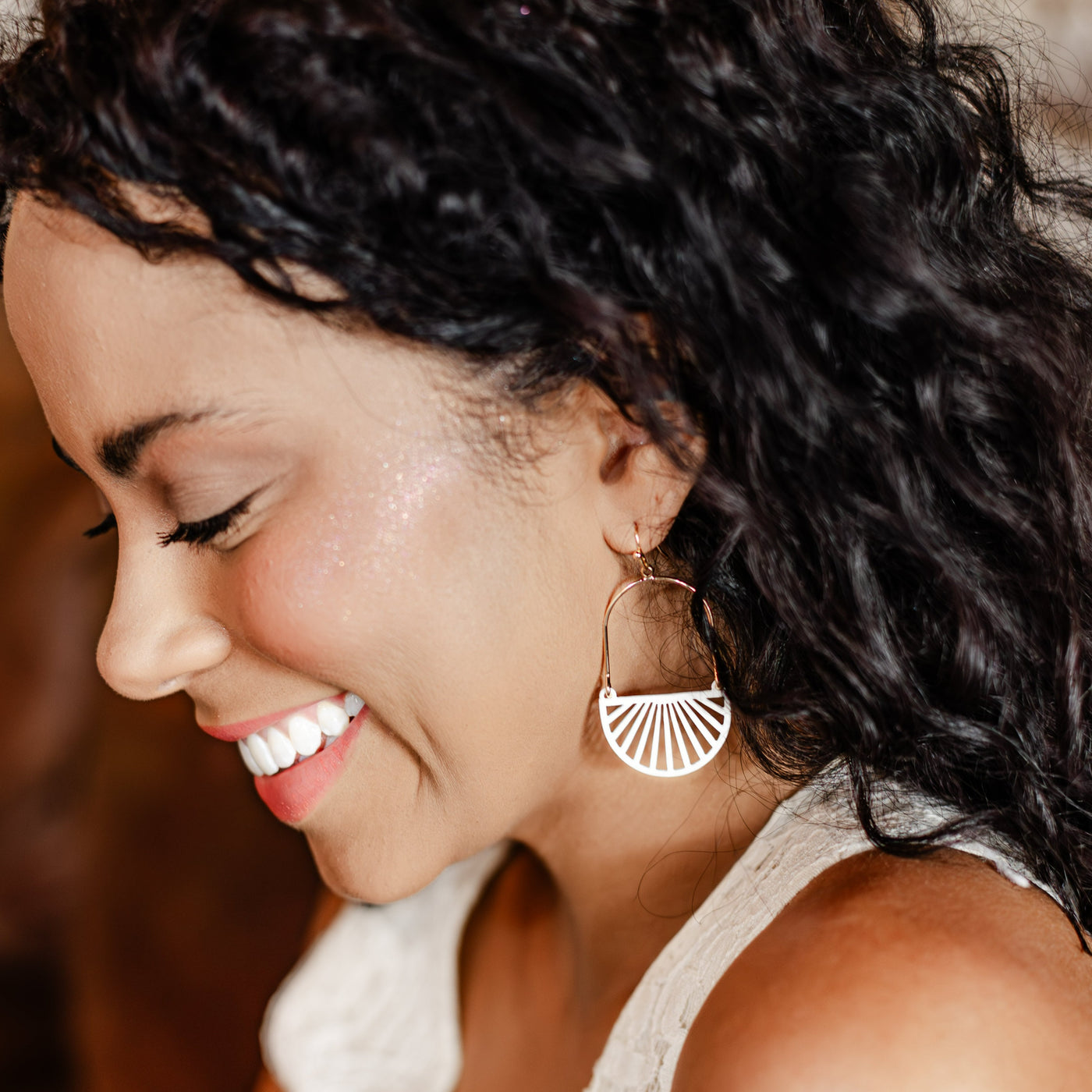 Our Iris Earrings feature an oval-shaped base with semi-circle sunbeams.  Pictured here on model in coffee shop. 