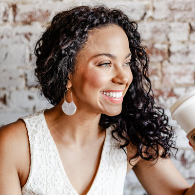 Sparkly white and gorgeous, our Birdie Earring is an open oval drop hoop that is sure to stun. With its geometric feel and white marbled shiny finish shown featured on a model. 