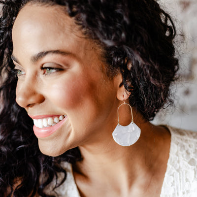 Sparkly white and gorgeous, our Birdie Earring is an open oval drop hoop that is sure to stun. With its geometric feel and white marbled shiny finish shown featured on a model.