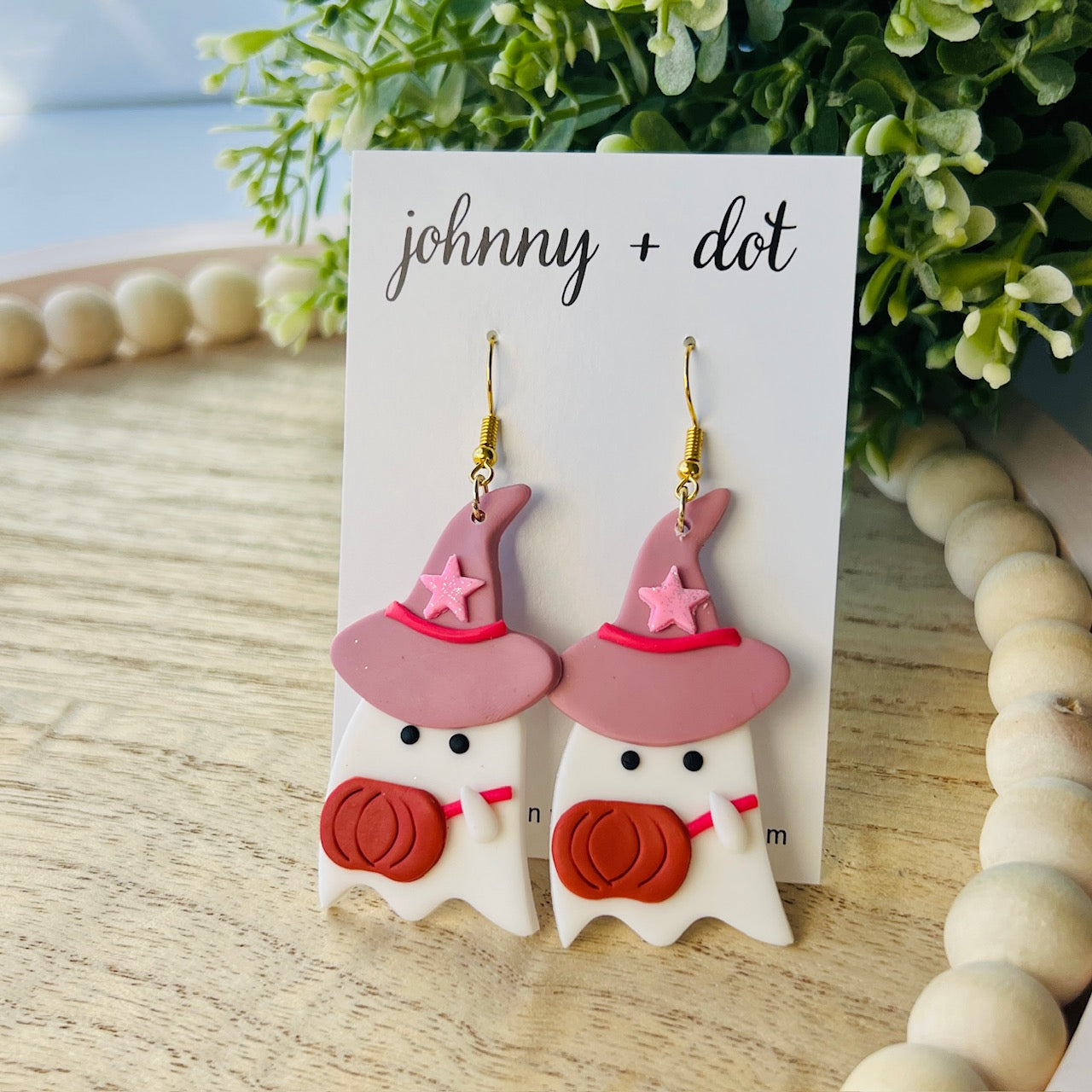 Halloween-themed ghost earrings with pink hats and pumpkin outfits on a 'johnny + dot' card.