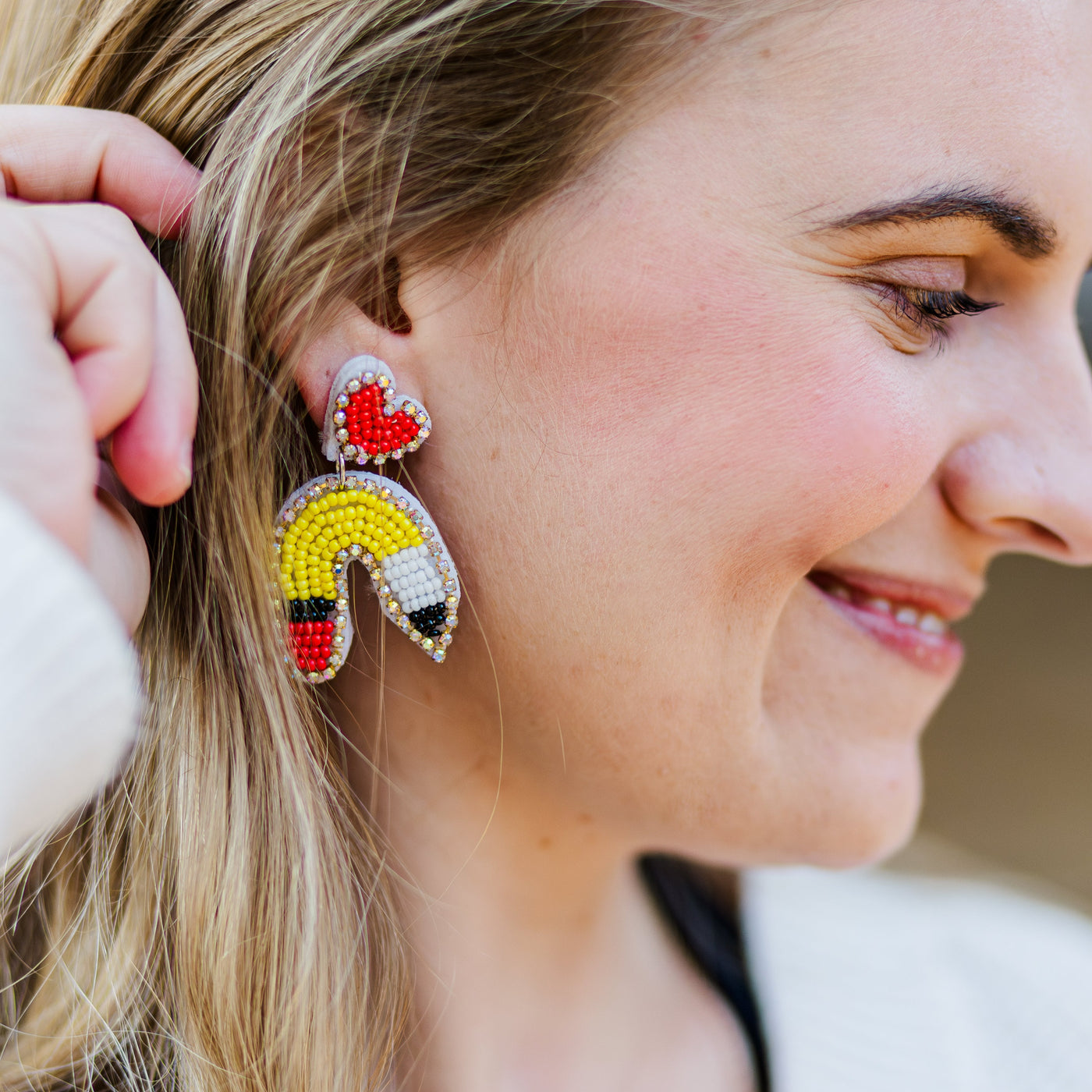 Model wearing pair of beaded pencil u-shaped teacher earrings. 