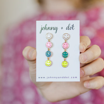 Model holding Multi-Colored Happy Face Dangle Earrings