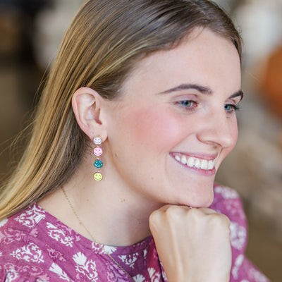 Model holding Multi-Colored Happy Face Dangle Earrings