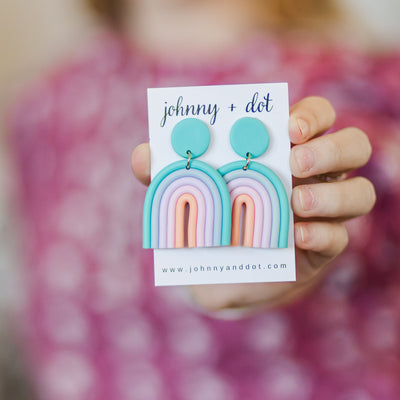 Model holding Aqua Rainbow Clay Earrings.