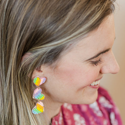 Model wearing a pair of Beaded Pastel Heart Trio Dangle Earrings.