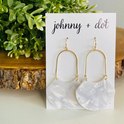 An open oval drop hoop earring with gold hardware and a white marble acetate finish displayed on a Johnny & Dot earring card. 