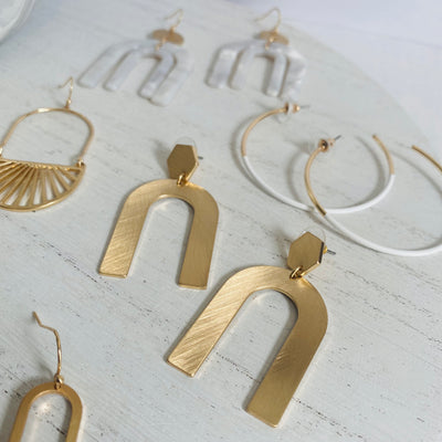 A college of gold and white dangle earrings.